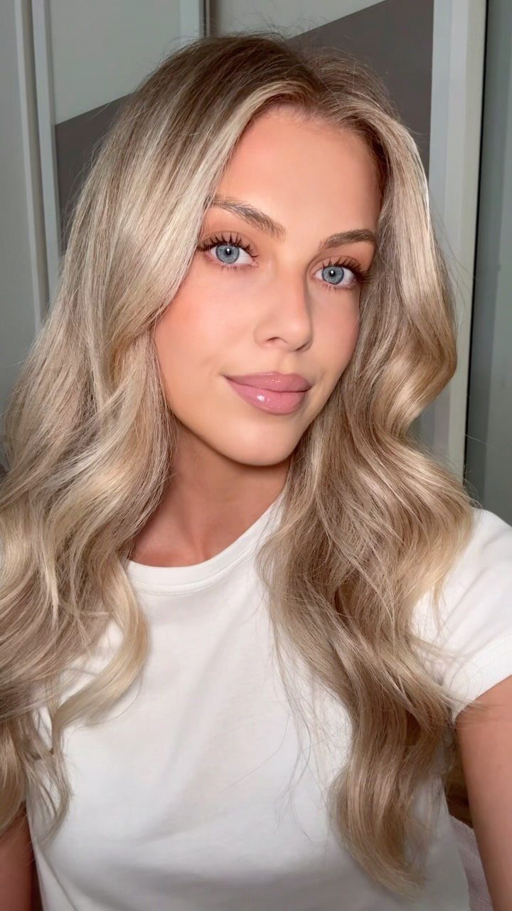 Woman with blonde hair and blue eyes wearing light pink lipstick and makeup.