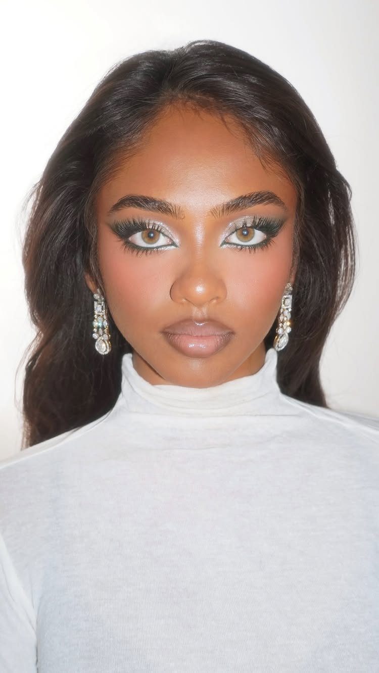 Woman with shimmery silver eyeshadow and winged eyeliner wearing a white turtleneck.