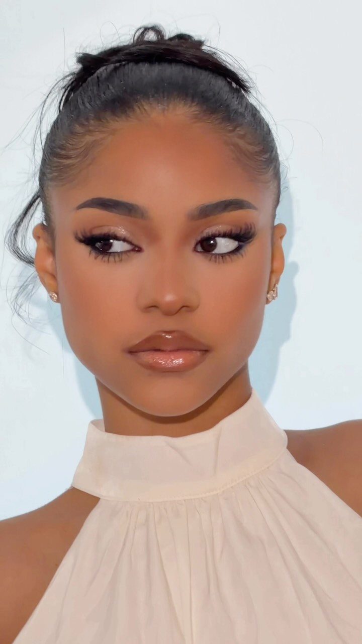 Woman with glamorous makeup, winged eyeliner, and glossy lips posing for a portrait