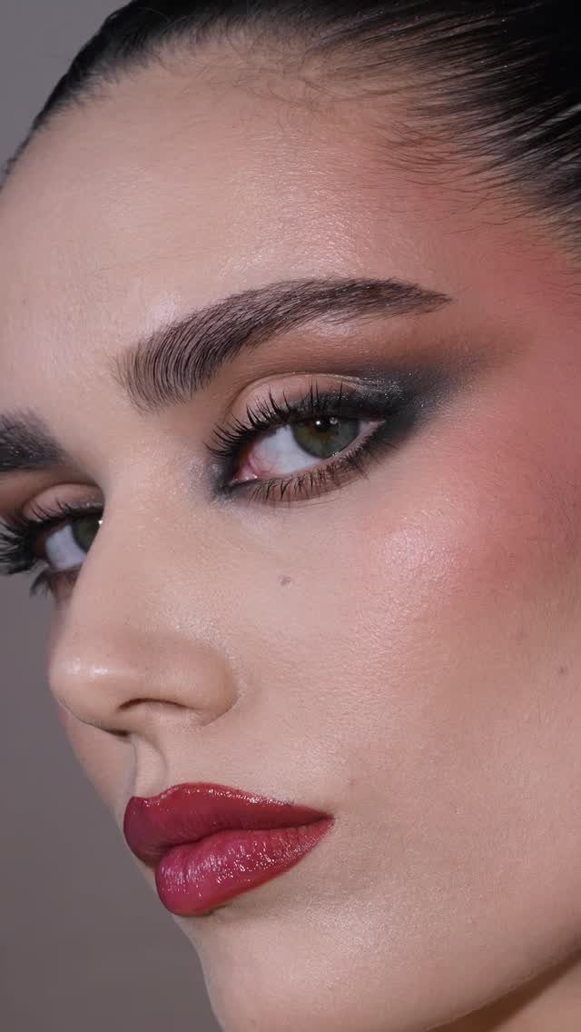 Woman with smoky eye makeup, berry red lips, and berry-toned blush on cheeks.