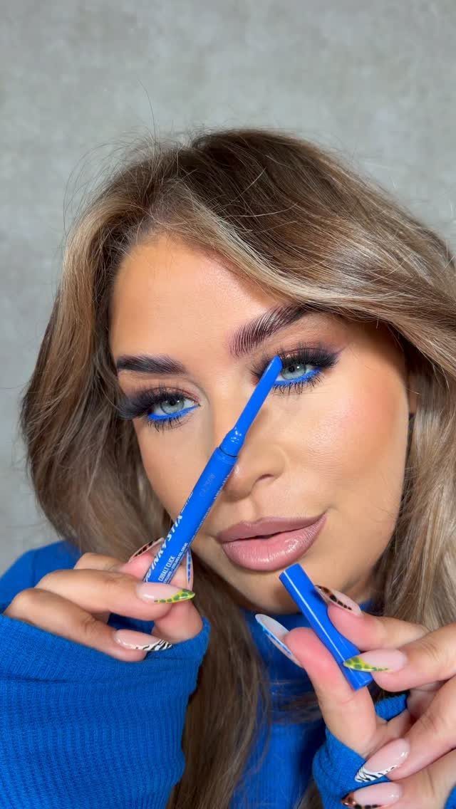 Woman with bright blue eyeliner on her lower waterline holding a blue pencil.
