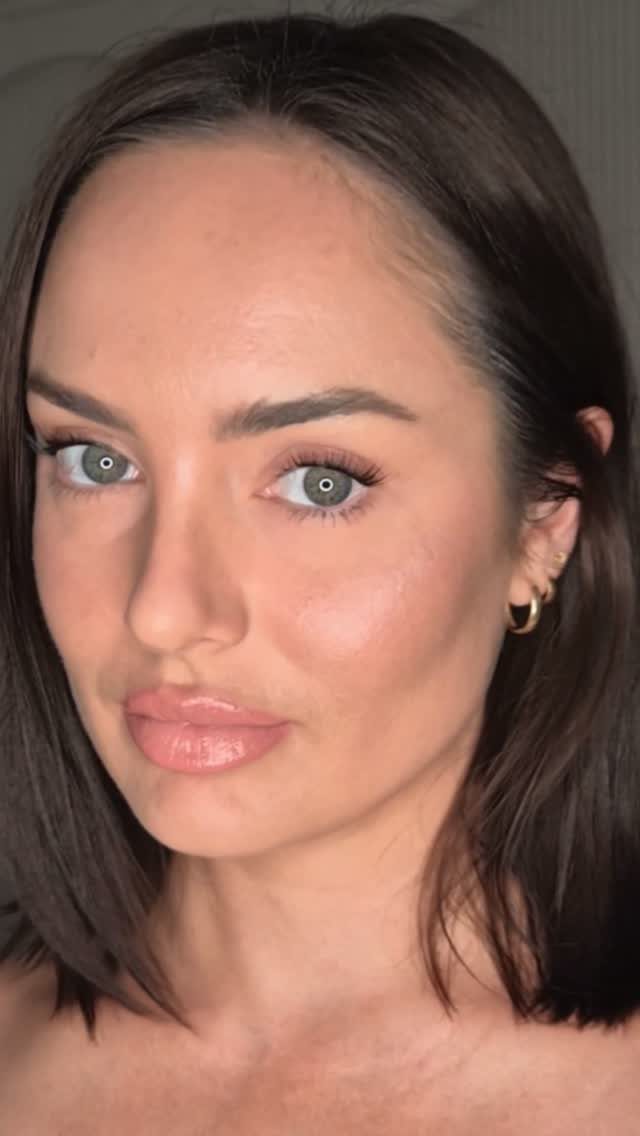 Woman with glowing skin and minimal makeup wearing glossy nude lipstick