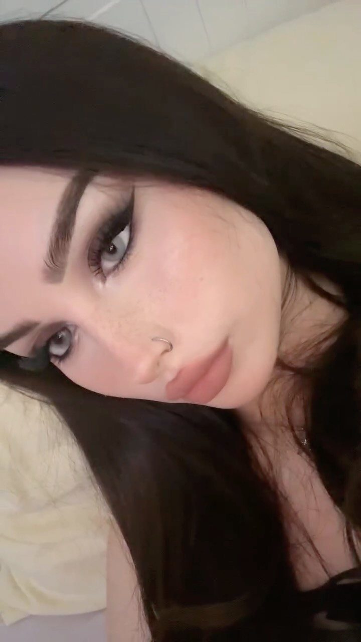 Woman with long dark hair wearing thick black winged smoky eyeliner and nude lips.