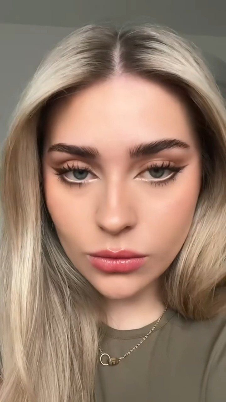 Woman with blonde hair wearing white eyeshadow along her lower lash line.