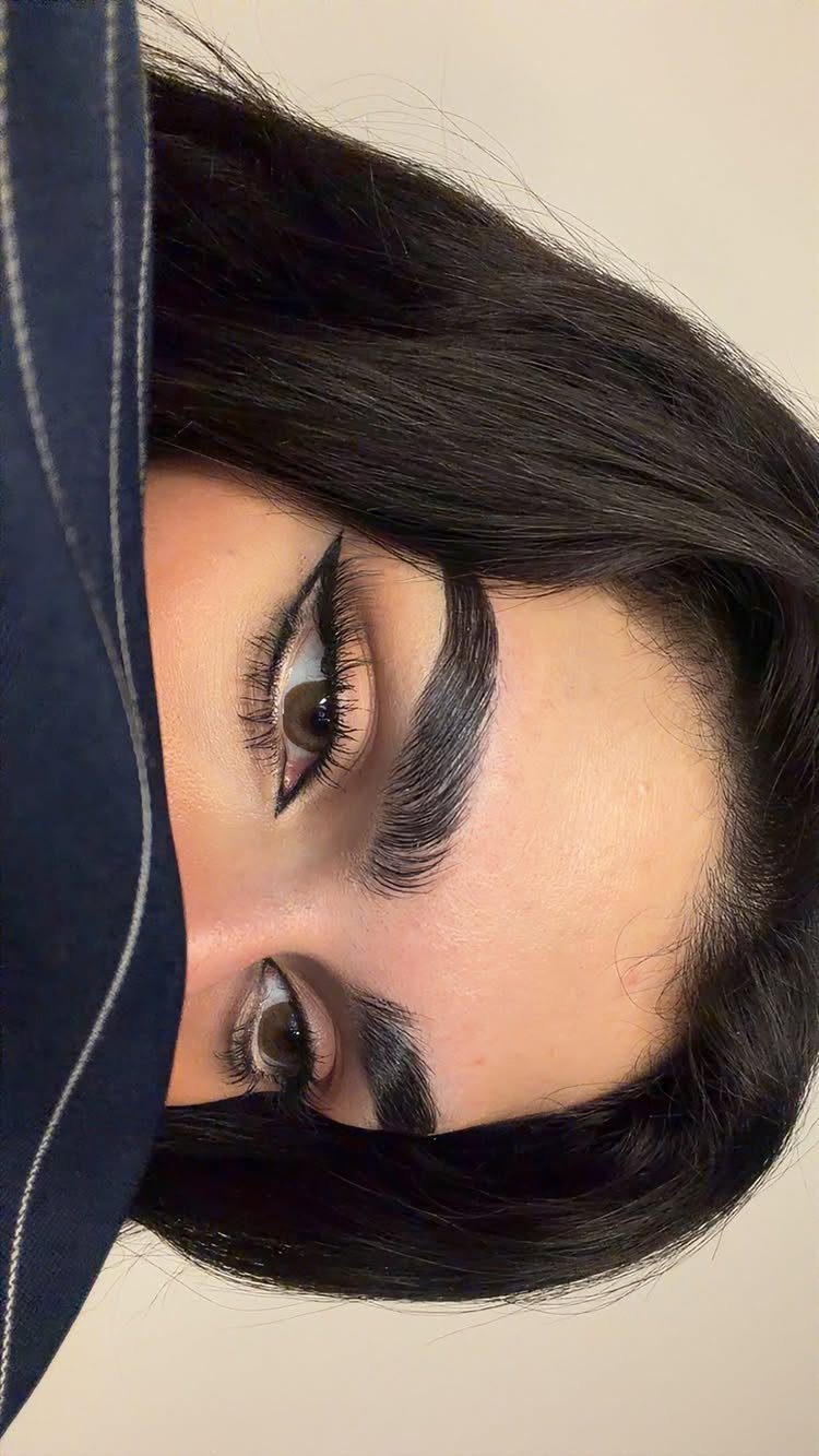 Eyes with winged eyeliner and long false eyelashes on a person with black hair