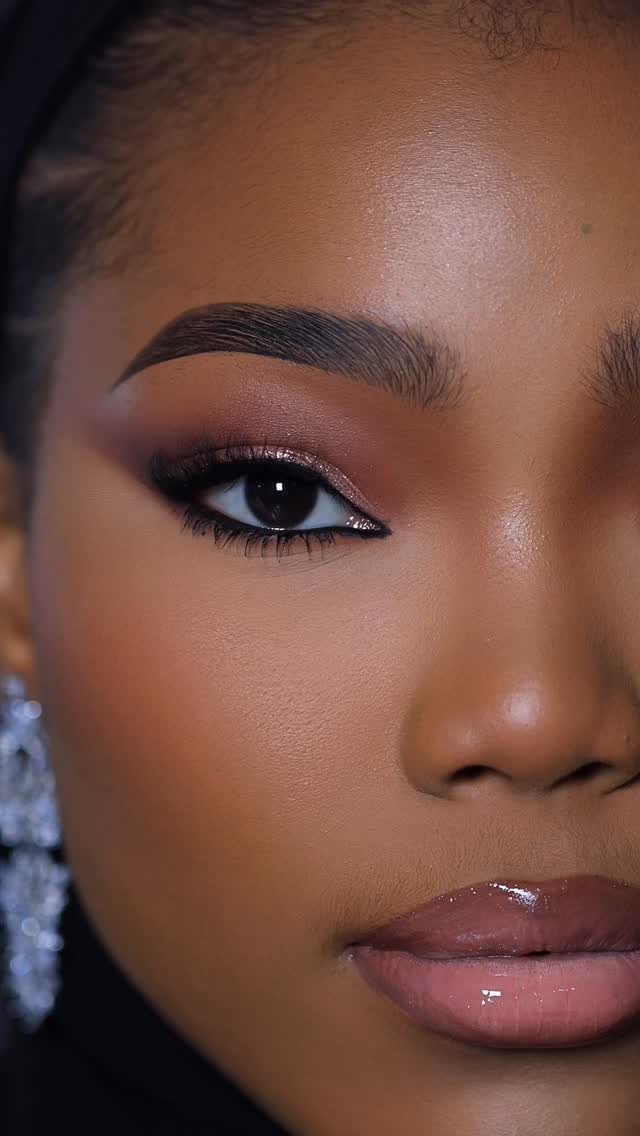 Person with brown skin wearing winged eyeliner and glossy nude lipstick.