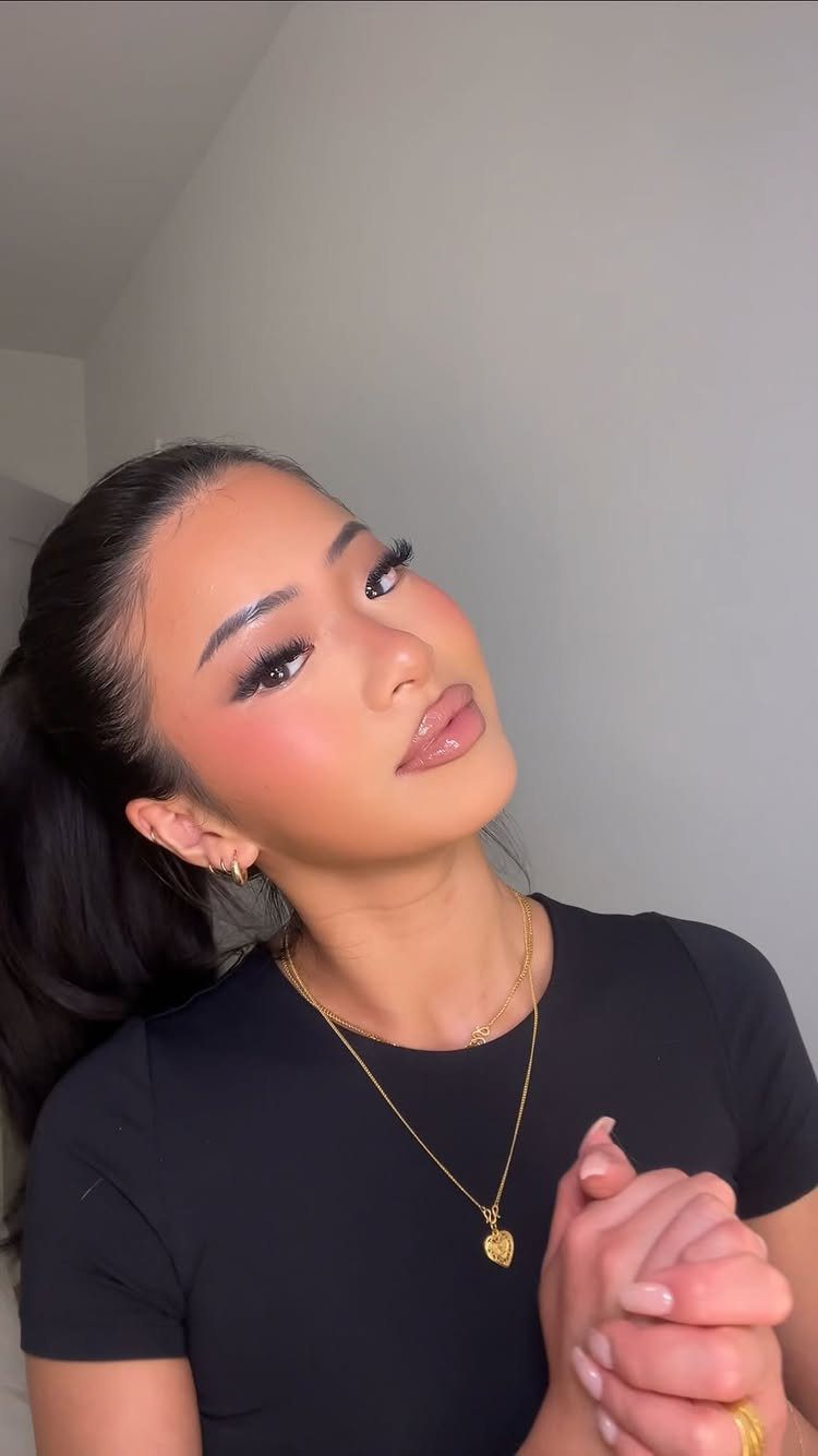 Woman with brown skin showcasing a full face of highlighting and contouring makeup.