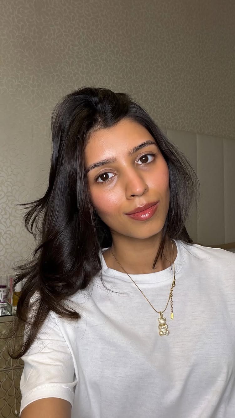 Woman with brown skin wearing minimal natural makeup and a white t-shirt.