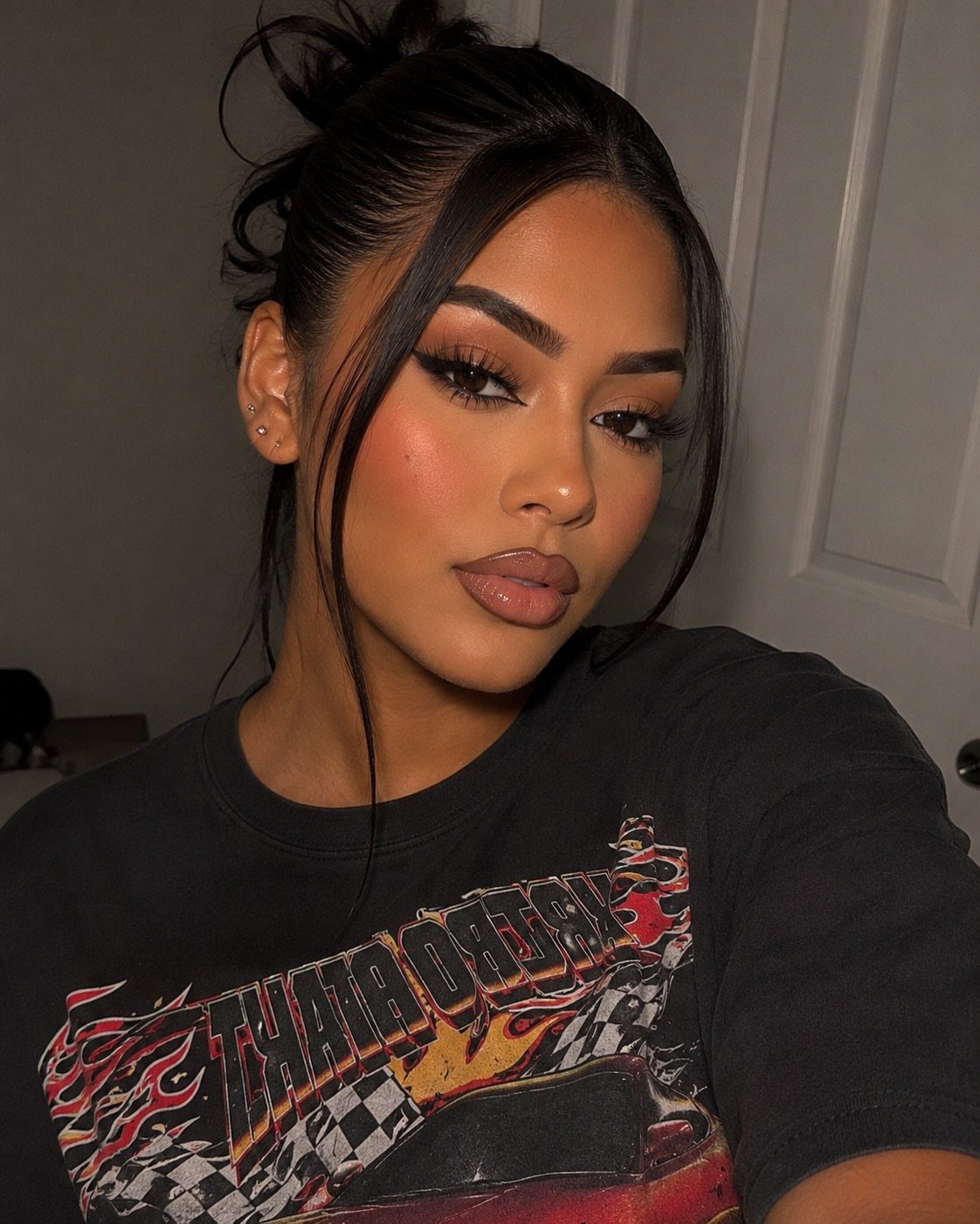 Woman with dark skin wearing a nude makeup look and black graphic tee