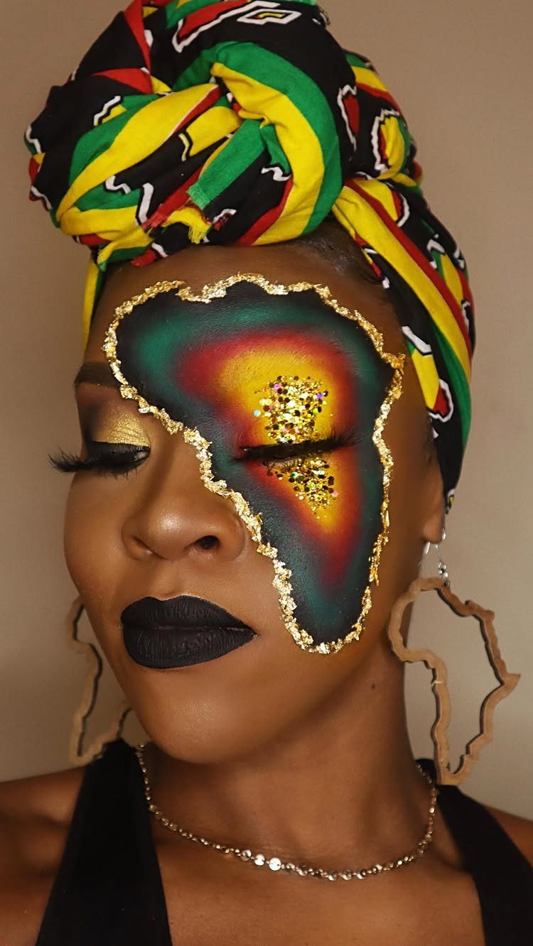 Woman with Africa-shaped face makeup in red, yellow, and green with gold glitter.