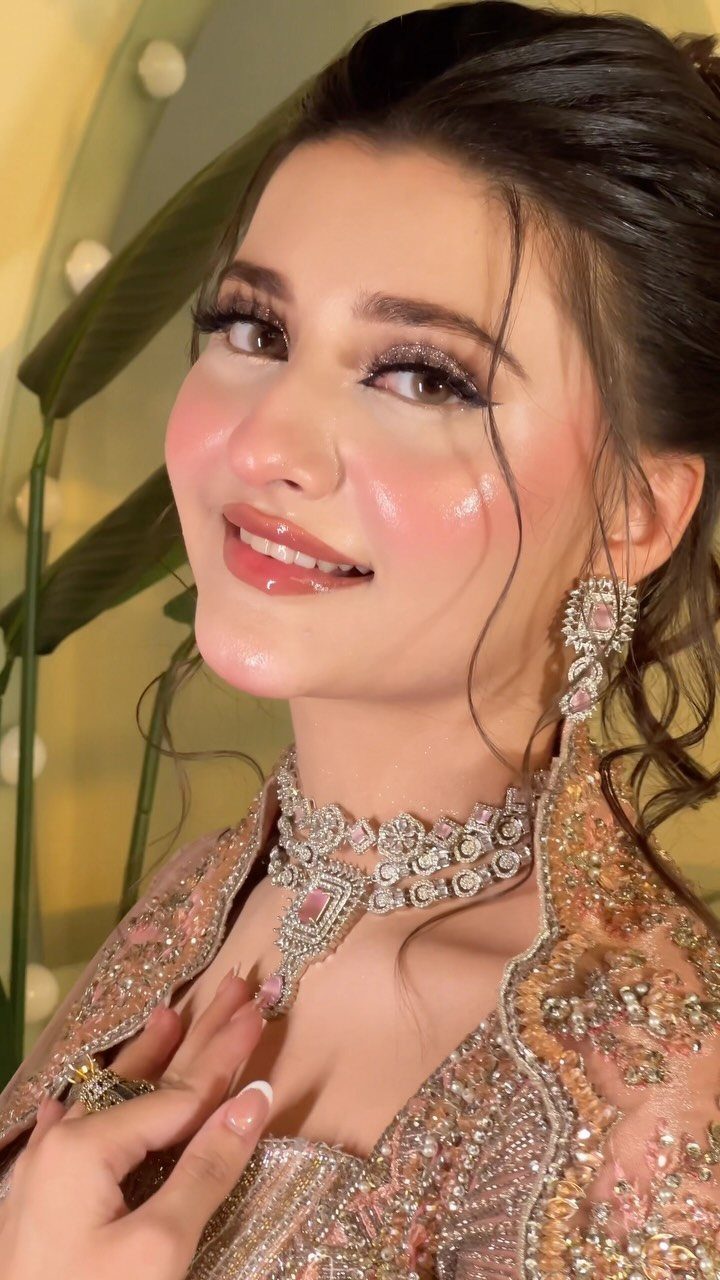Woman with shimmering eyeshadow and glossy makeup wearing ornate peach beaded attire.