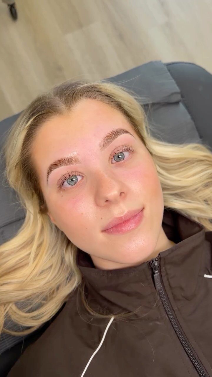 Blonde woman with light blue eyes and natural feathered eyebrows posing for portrait