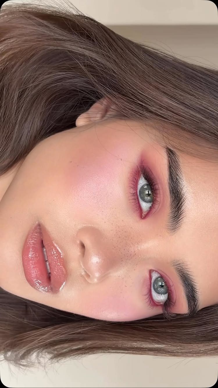 Woman with monochromatic pink makeup on her eyes, cheeks, and glossy lips.