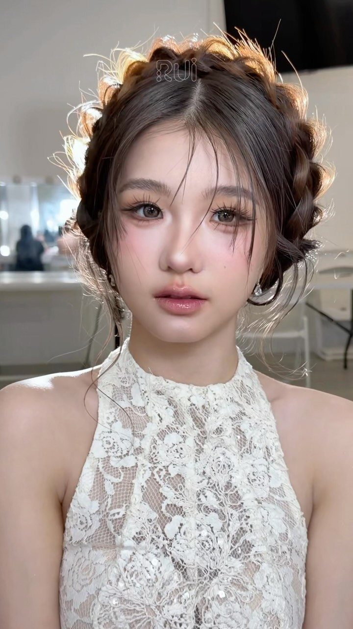 Young woman with braided crown hair and soft pink makeup wearing white lace.