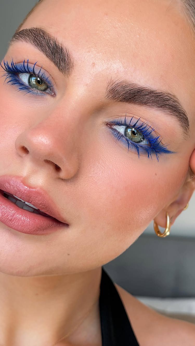 Woman with vivid cobalt blue eyeliner and mascara and neutral pink lips.