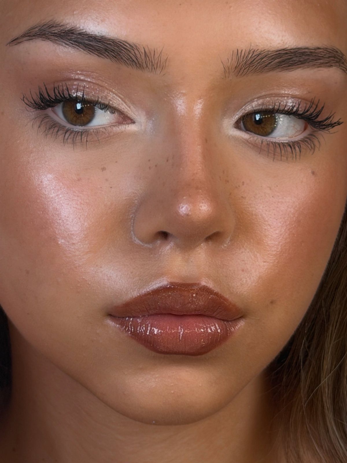 Natural Bronzy Makeup Looks: 10 Warm Glow Ideas 8 Woman with glowing bronzed skin, shimmering gold eyeshadow, and glossy brown lips.