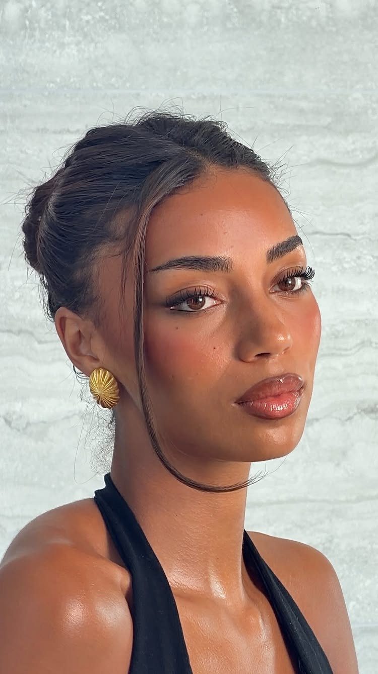 Natural Bronzy Makeup Looks: 10 Warm Glow Ideas 9 Woman with glowing bronzed makeup, glossy lips, and gold shell earrings posing.