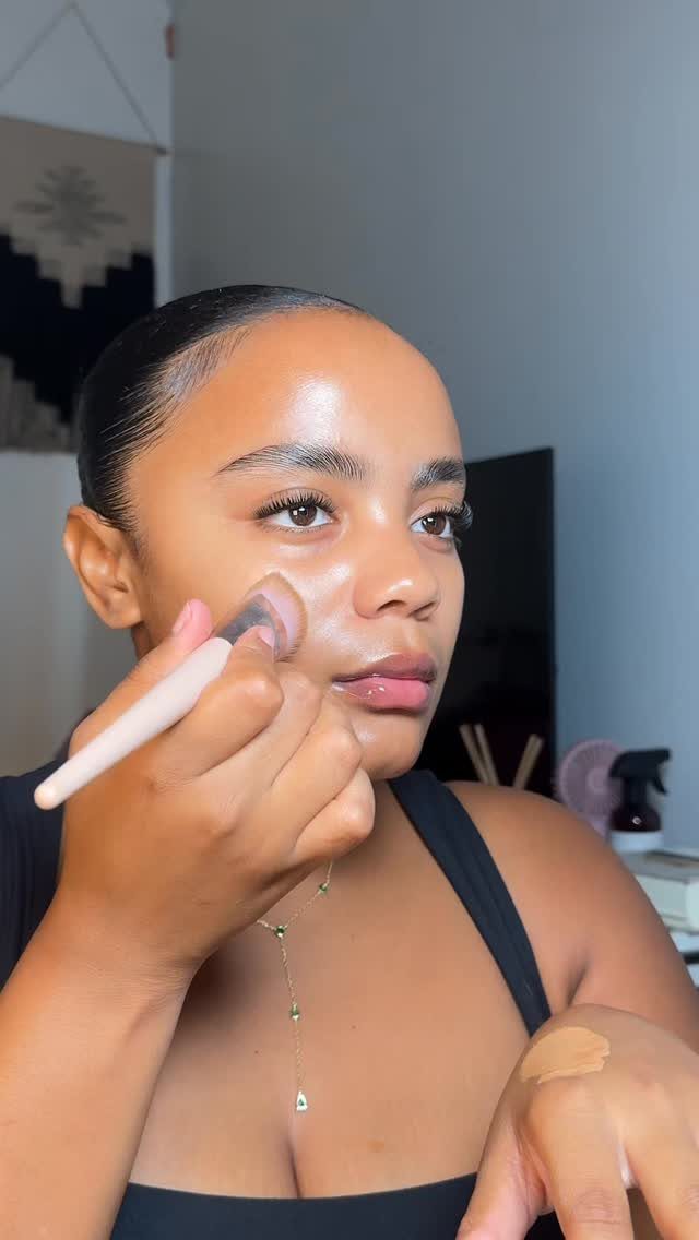 Woman applying highlighter to her cheek for a natural glowy makeup look.