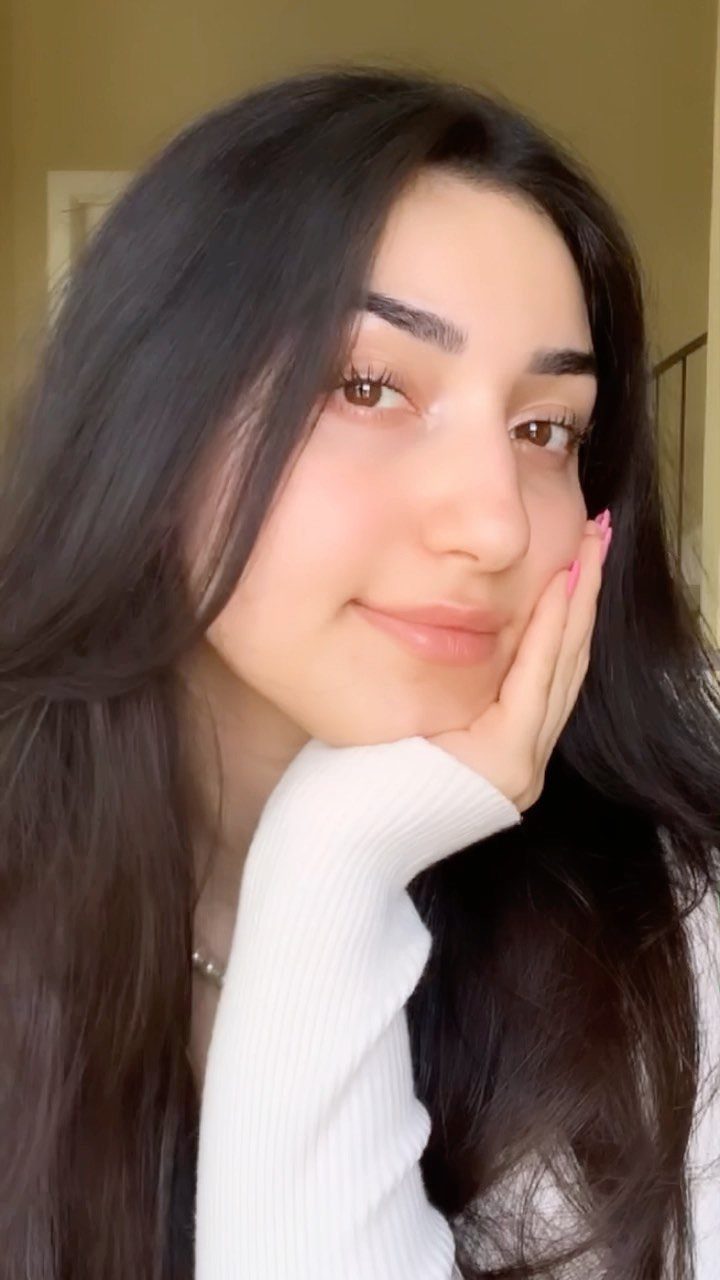 Woman with long dark hair and defined natural fluffy eyebrows posing for portrait