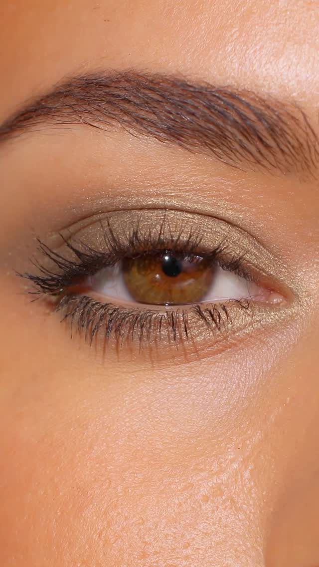 Close-up of an eye with shimmering gold eyeshadow and defined mascara lashes.