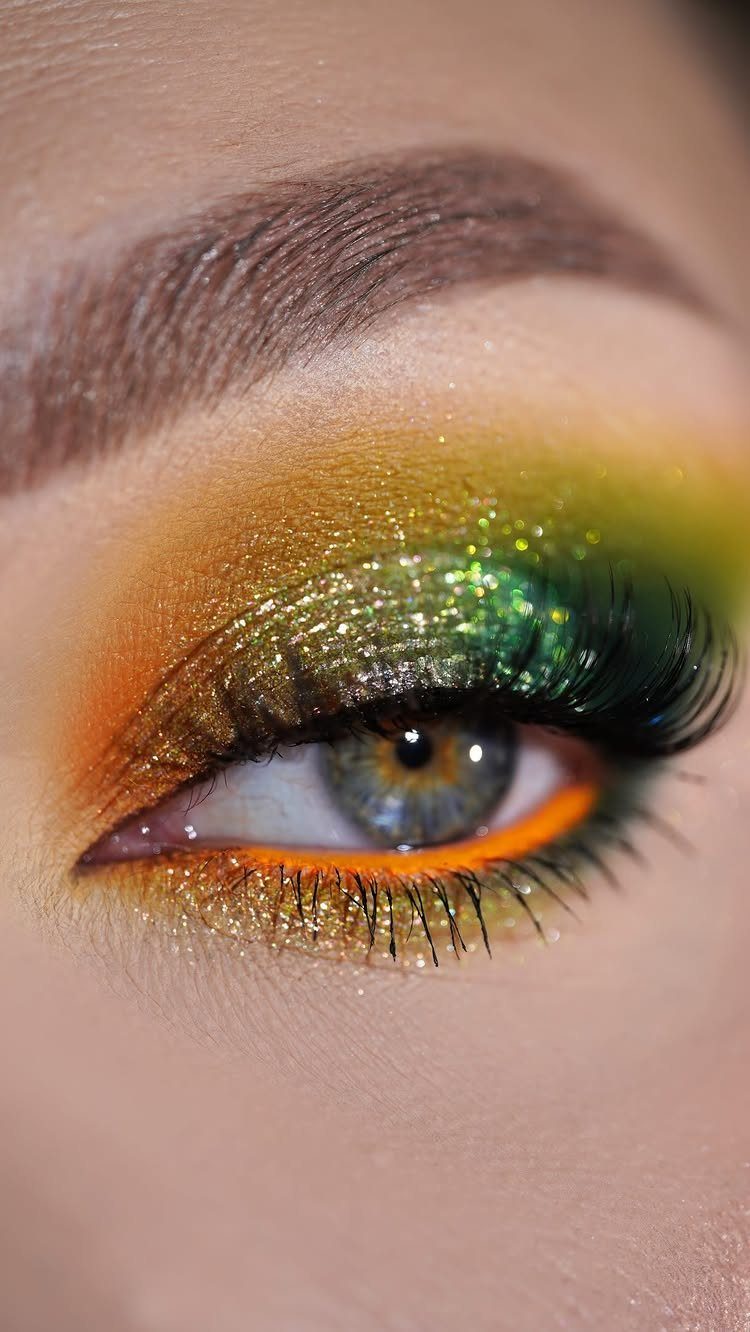 Eye with sparkling orange and lime green glitter eyeshadow and bold lower liner.