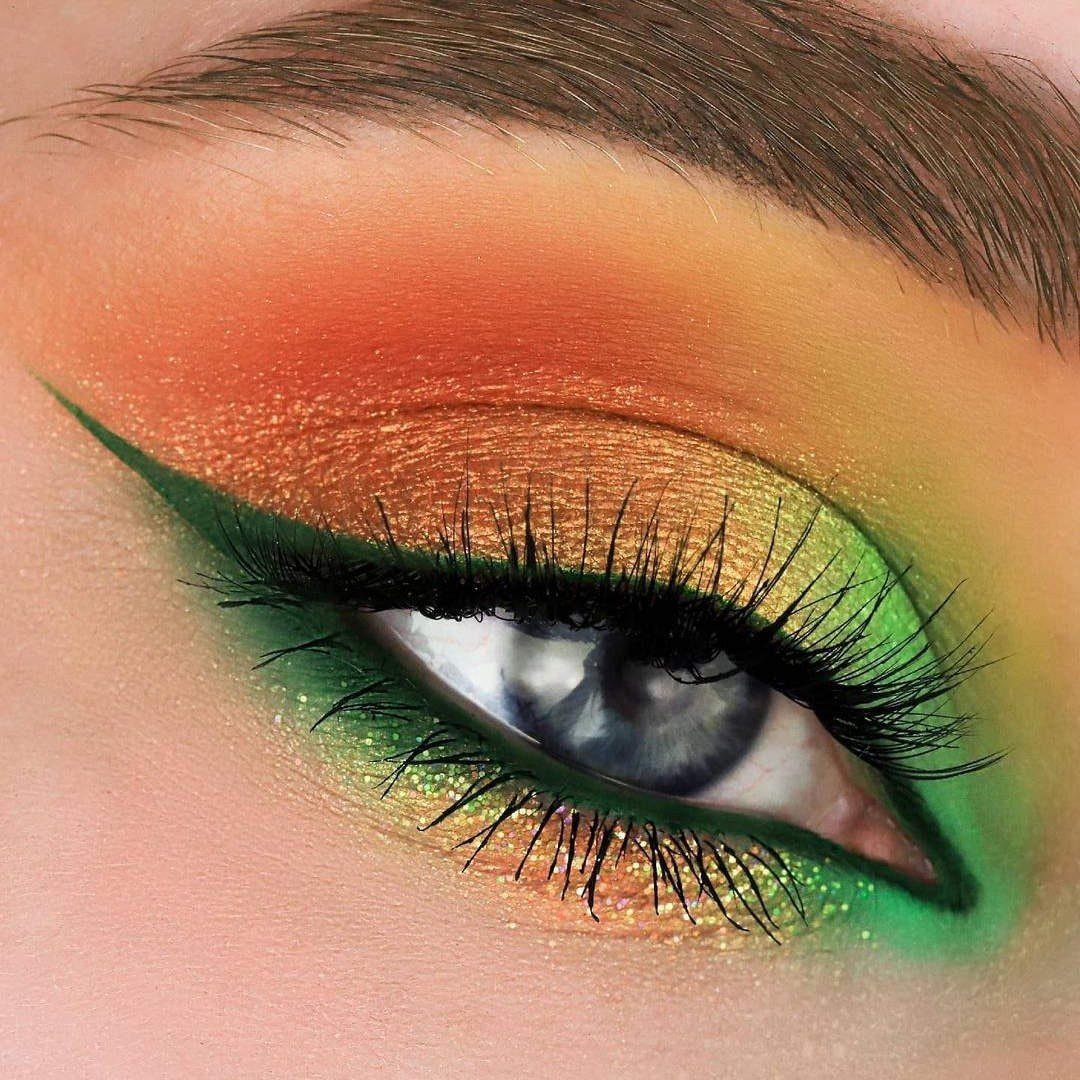 Eye with vibrant orange and lime green eyeshadow and sharp green eyeliner.