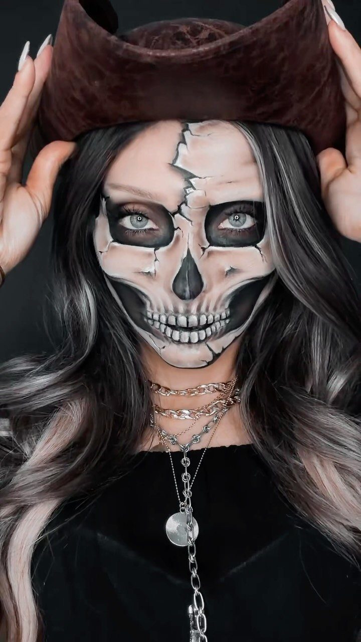 Woman with skull face makeup wearing a brown pirate hat and black clothing.
