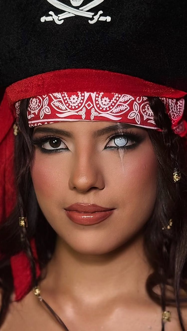 Woman in pirate costume with dramatic eye makeup and a white contact lens.