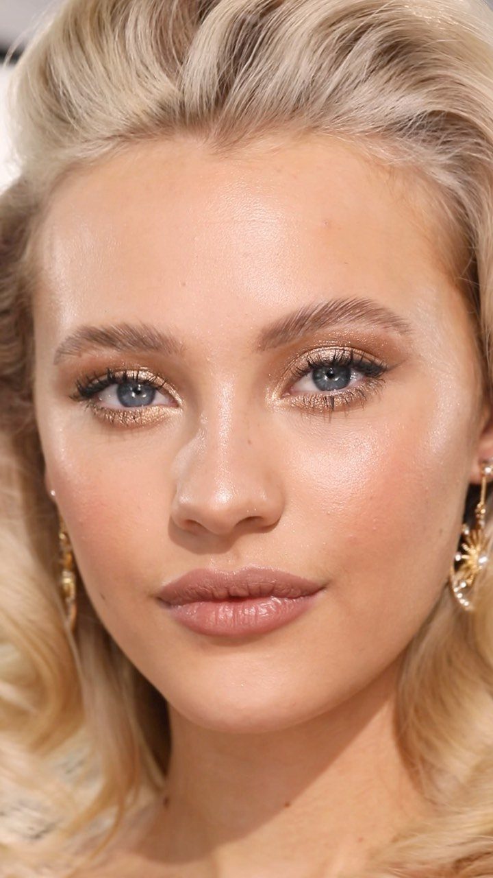 Woman with blonde hair wearing shimmering bronze eyeshadow and glowing nude makeup.