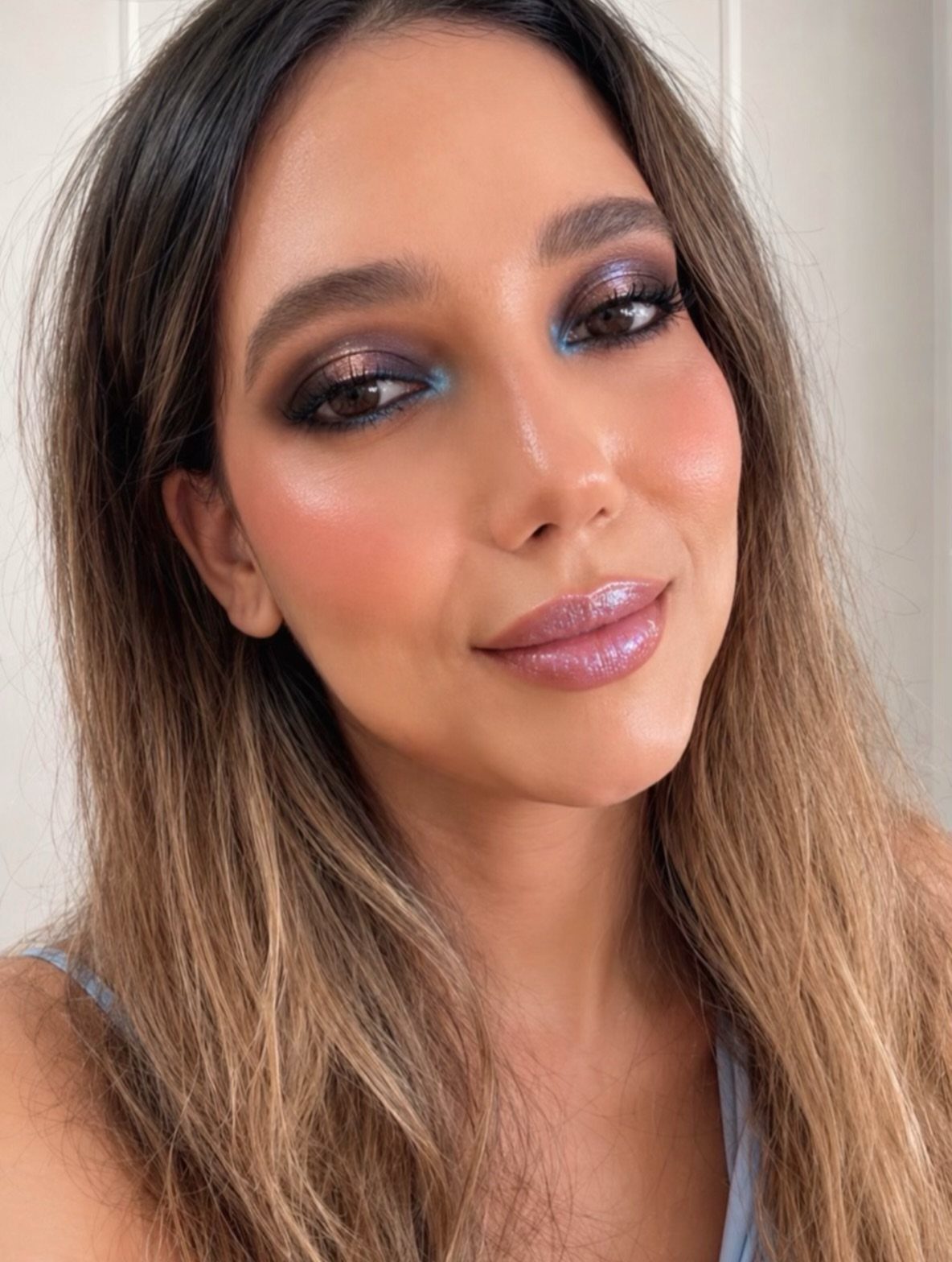 Woman with shimmering purple and blue eyeshadow and glossy purple lips.