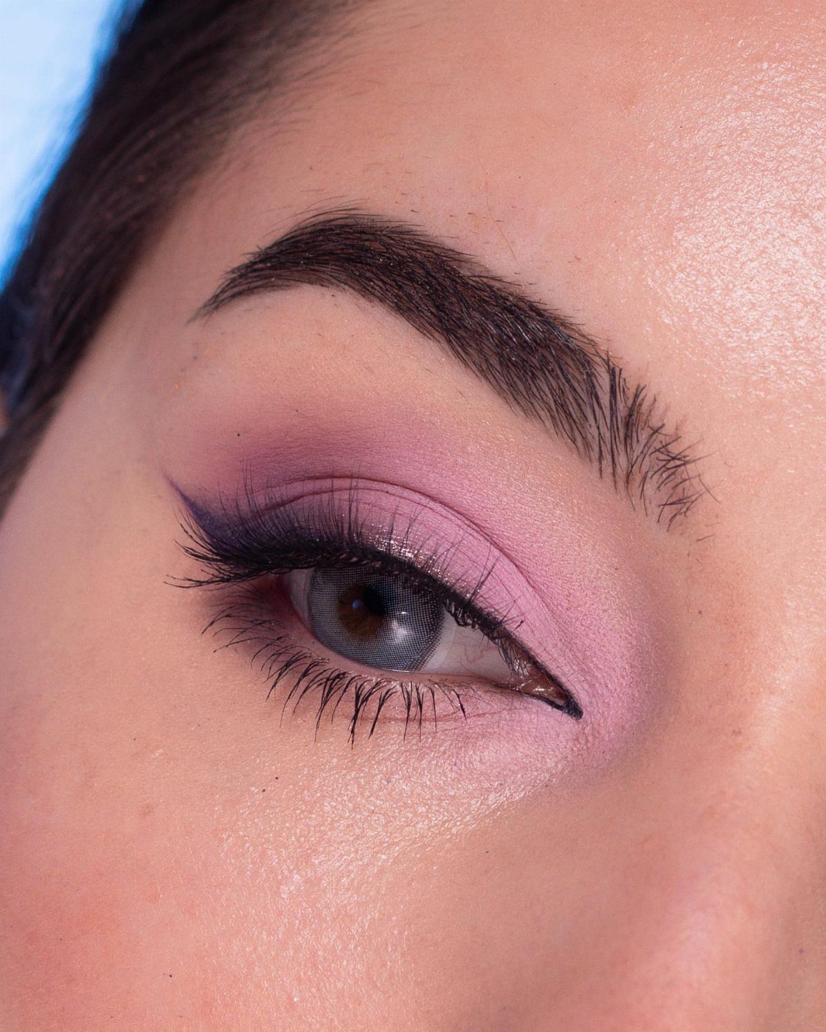Close-up of a blue eye with blended purple and pink eyeshadow and eyeliner.