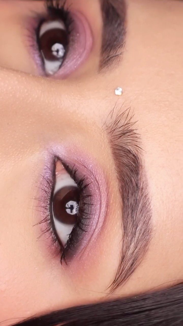 Eyes with blended purple smokey eyeshadow, long lashes, and a brow rhinestone.