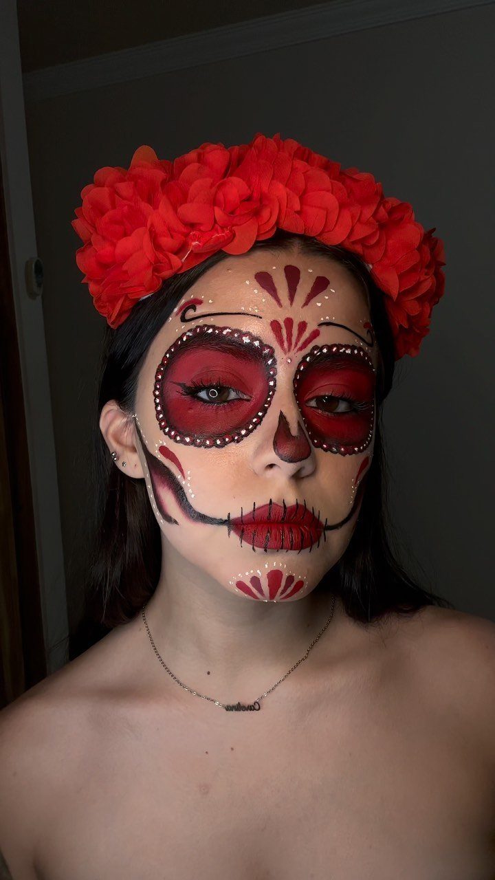 Woman with red Day of the Dead face paint and a red flower crown.