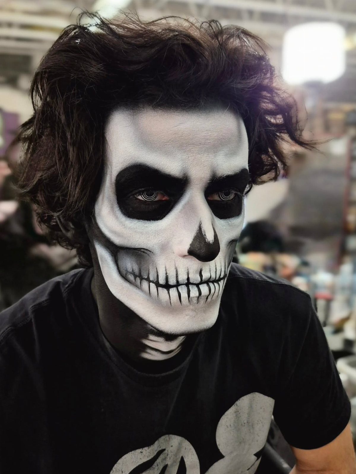 Person with messy dark hair wearing detailed black and white skeleton face paint.