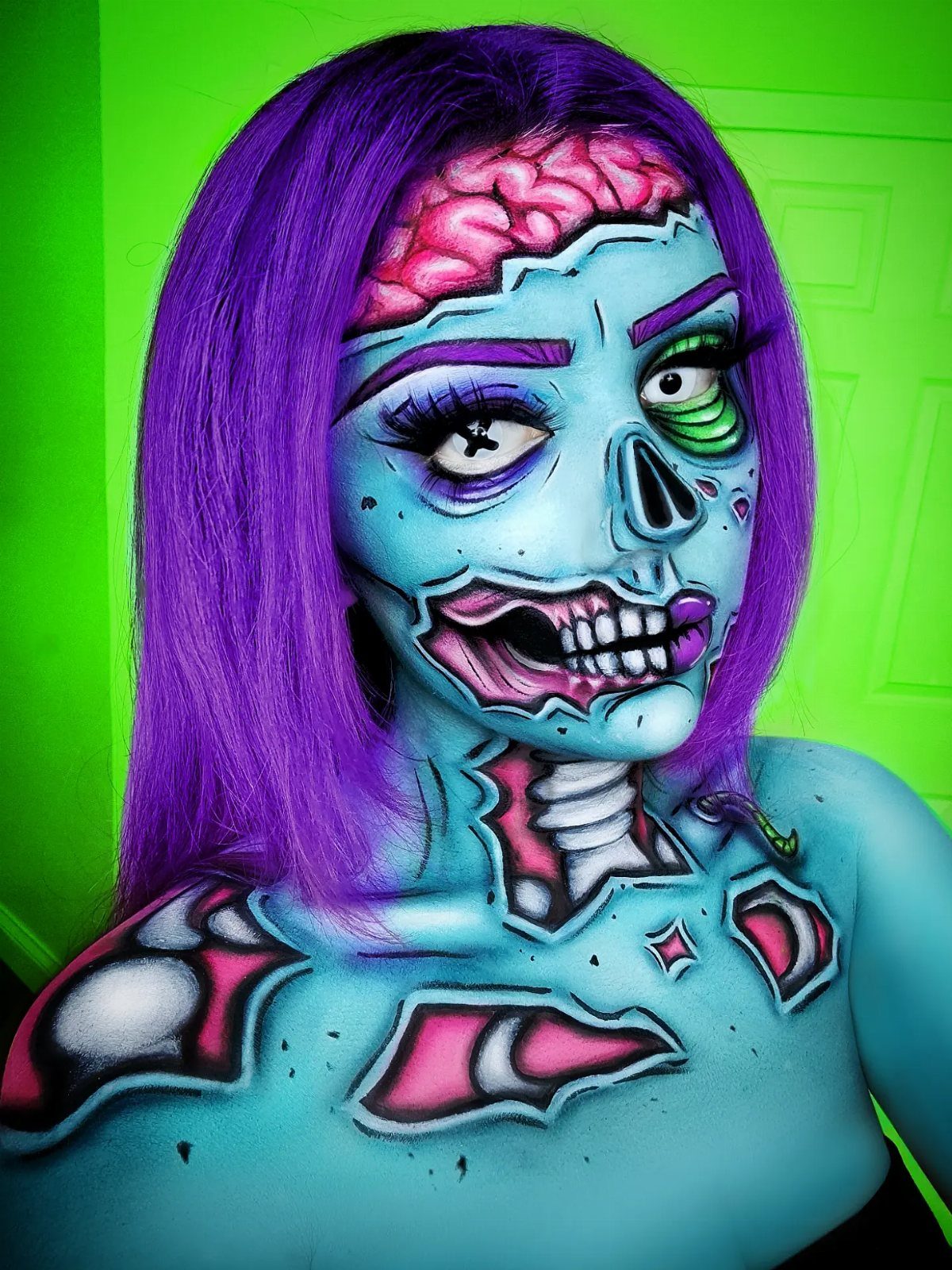 Person with blue zombie face paint, purple hair, and an exposed brain design.