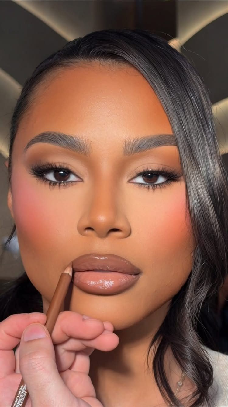 Woman receiving a soft glam makeup application with brown lip liner pencil