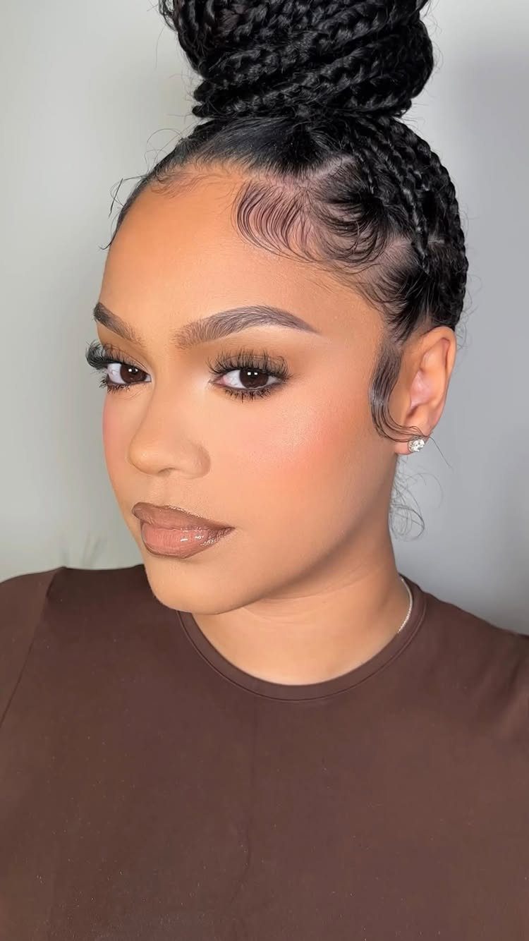 Woman with flawless skin and soft glam makeup wearing a braided high bun.