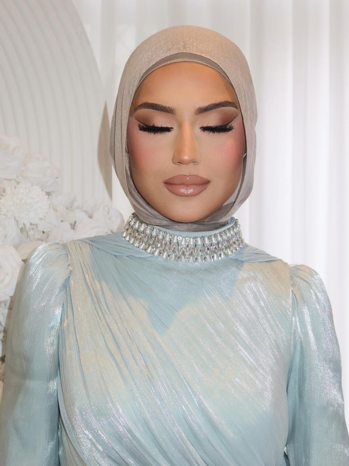 Woman in grey hijab and blue dress wearing soft glam makeup with neutral tones