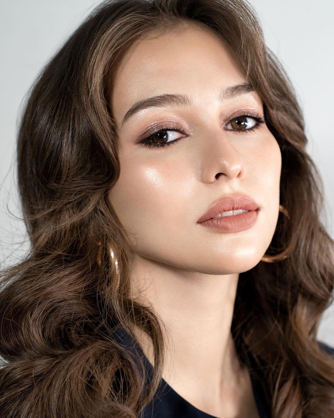Soft Sultry Makeup Ideas: 10 Looks for Day and Night 4 Woman with wavy brown hair wearing soft sultry makeup and highlighted cheekbones.