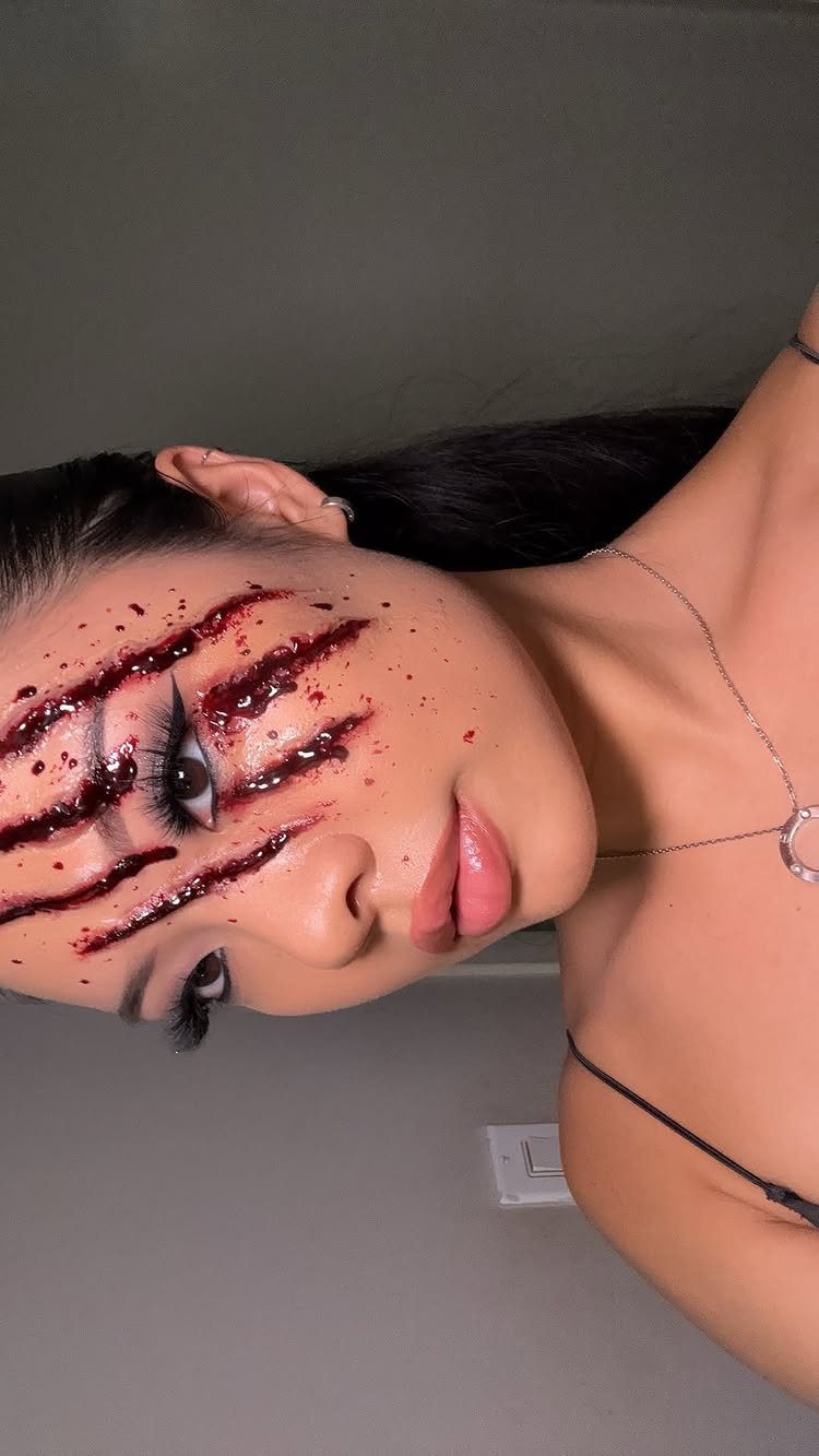 Woman with realistic fake bloody claw wounds and cuts on her face.