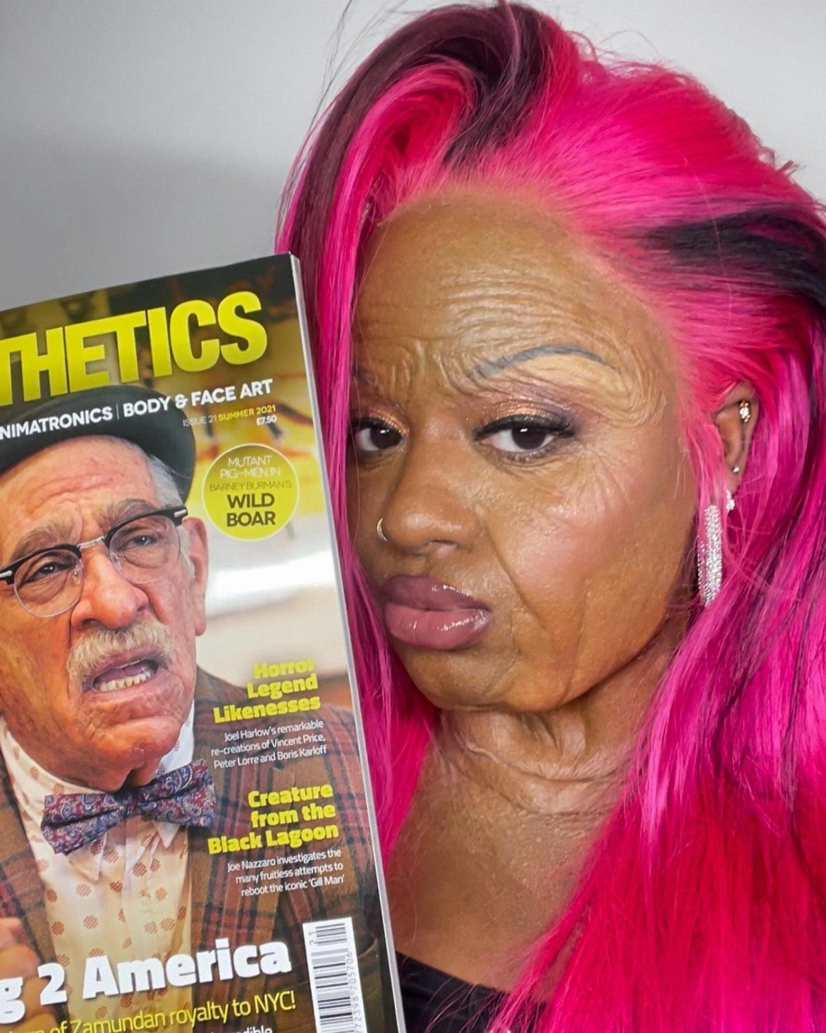 Person with pink hair wearing makeup that simulates aged, wrinkled, and sagging skin.