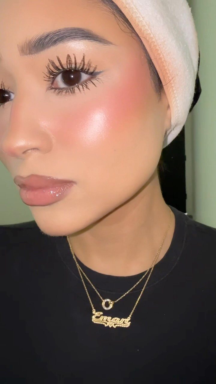 Woman with glowing makeup, highlighted cheeks, and glossy lips wearing a white head wrap.
