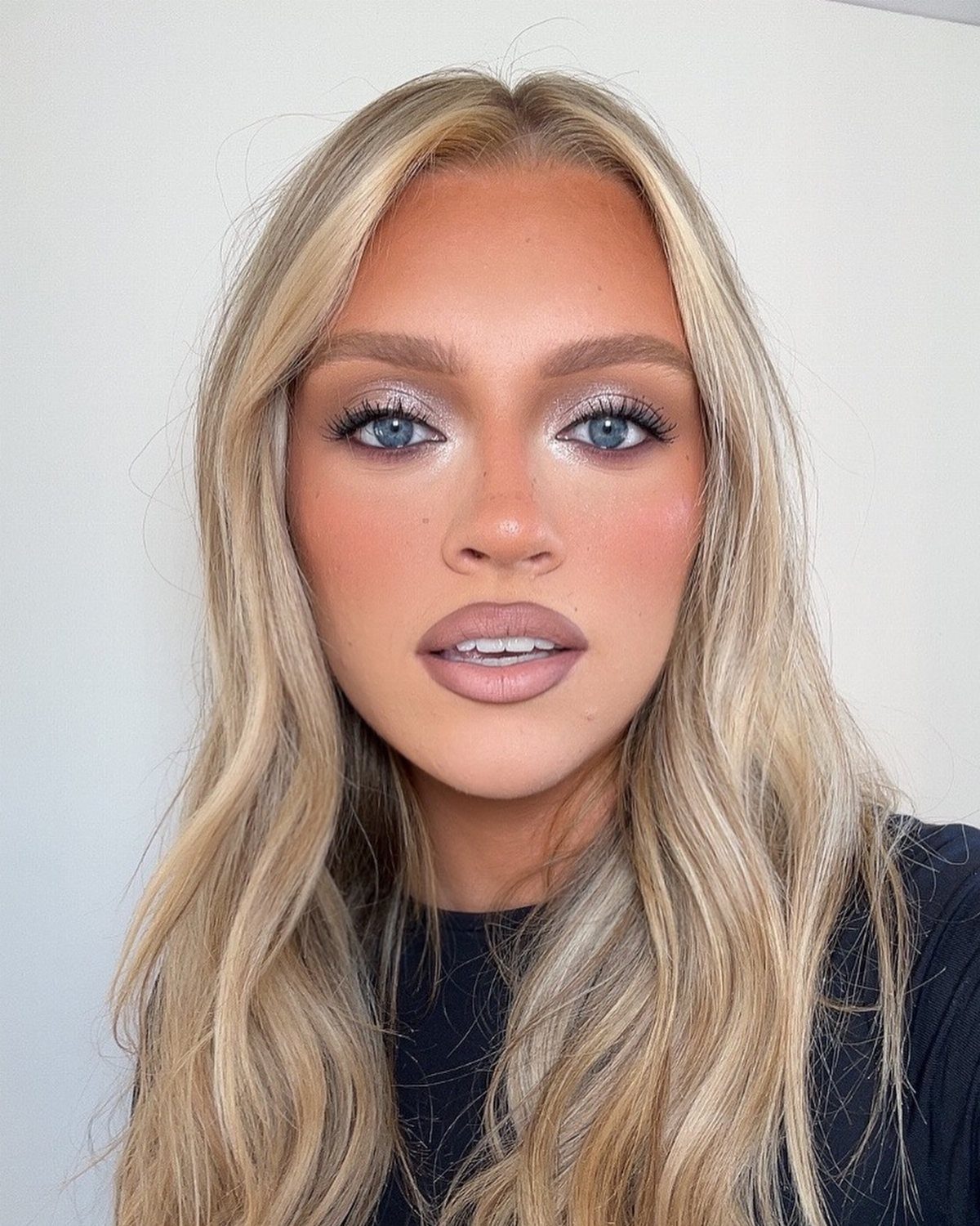 Woman with blonde hair wearing shimmering silver eyeshadow and matte mauve lipstick.