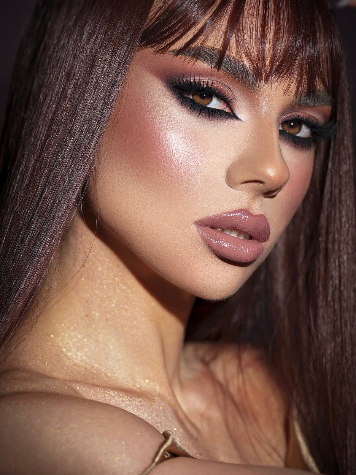 Woman with dark hair and bangs wearing a dramatic smoky eye makeup look