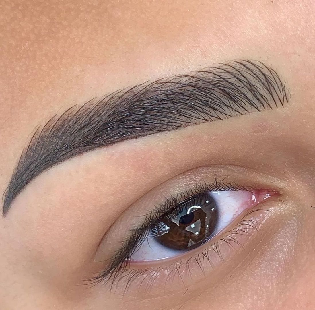 Well-defined dark brown eyebrow with a sharp arch above a brown eye.