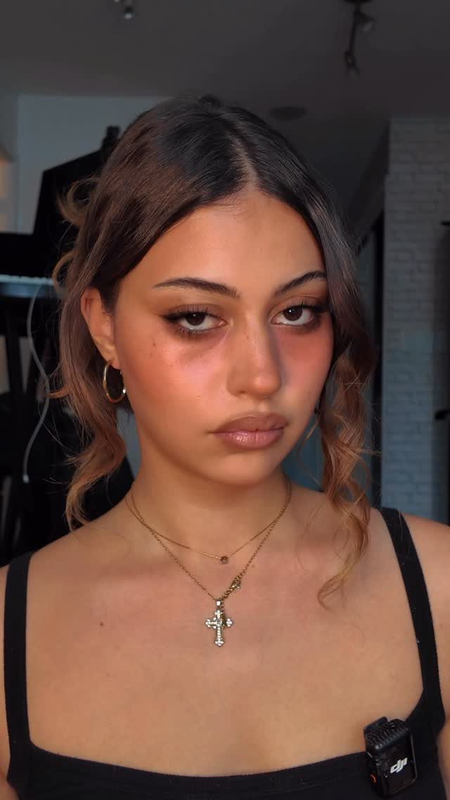 Woman with smudged dark eye makeup and thick black mascara on her lashes.