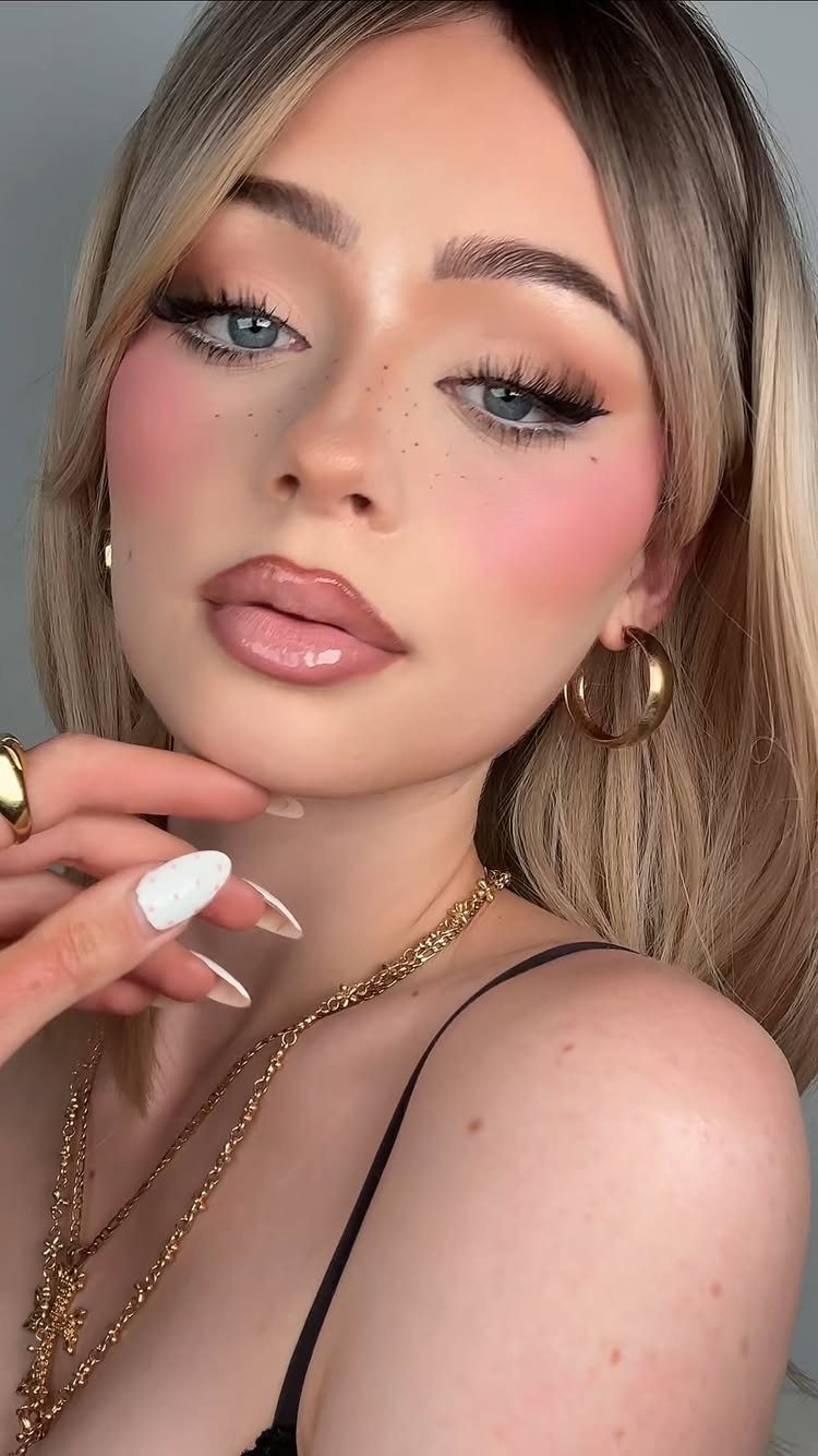 Woman with baddie aesthetic makeup, winged eyeliner, pink blush, and glossy lips.