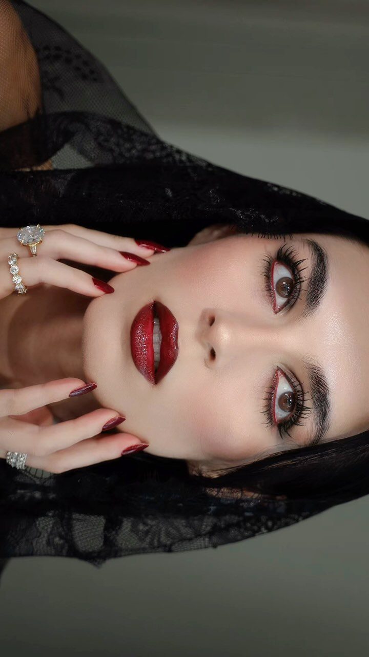 Vampire Eye Makeup Ideas: 8 Looks for Halloween Night 3 Woman with pale skin, red lipstick, and red eyeliner wearing a black lace veil.