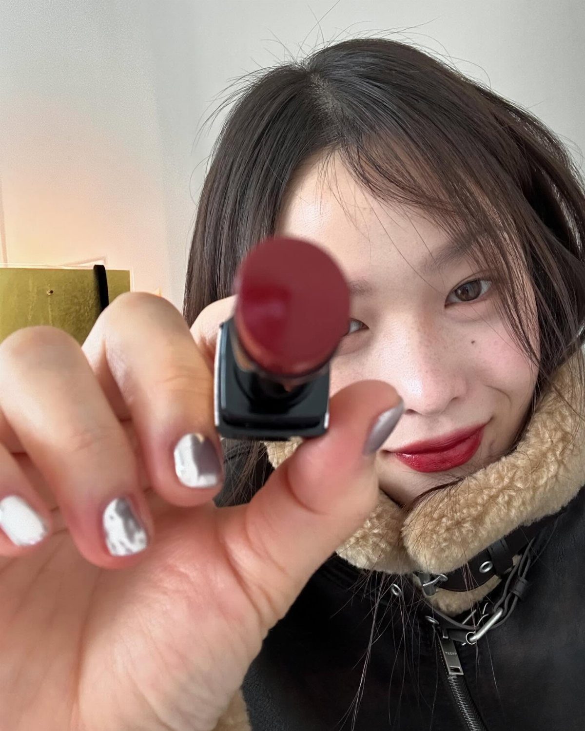 Warm Asian Makeup: 6 Peach, Coral and Red Ideas 5 Woman with deep red lips holding a matching red lipstick container close up