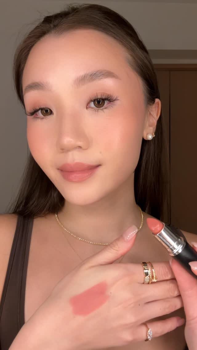 Warm Asian Makeup: 6 Peach, Coral and Red Ideas 3 Asian woman with peachy pink makeup showing a lipstick swatch on her hand